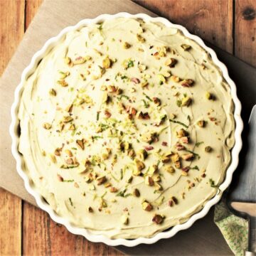Avocado cheesecake in pie dish with chopped pistachios on top.