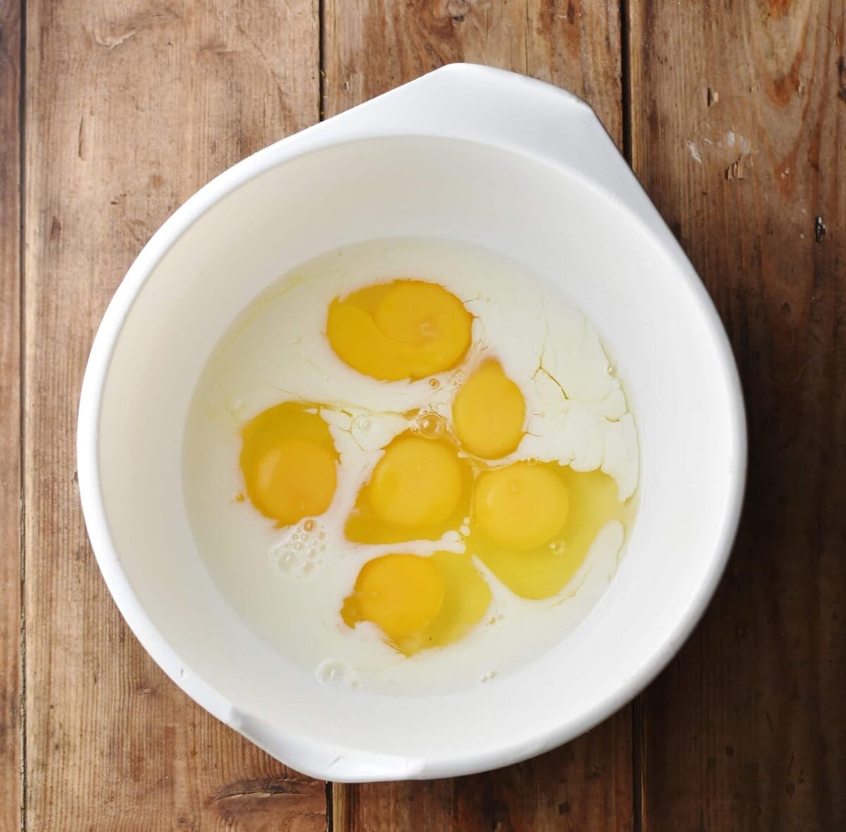 6 eggs and milk in large white bowl.