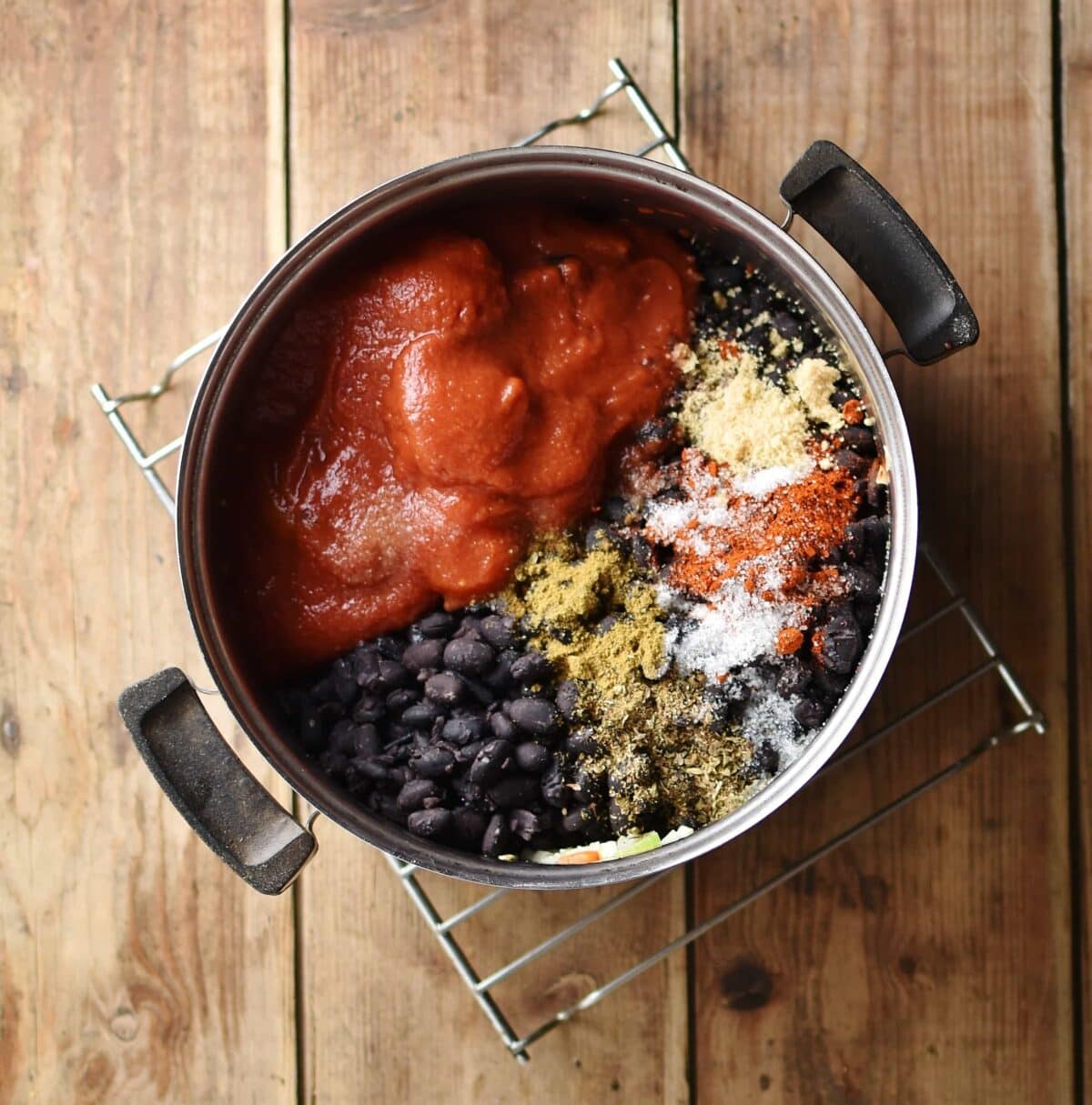 Beans, tomatoes and spices in pot on top of cooling rack.