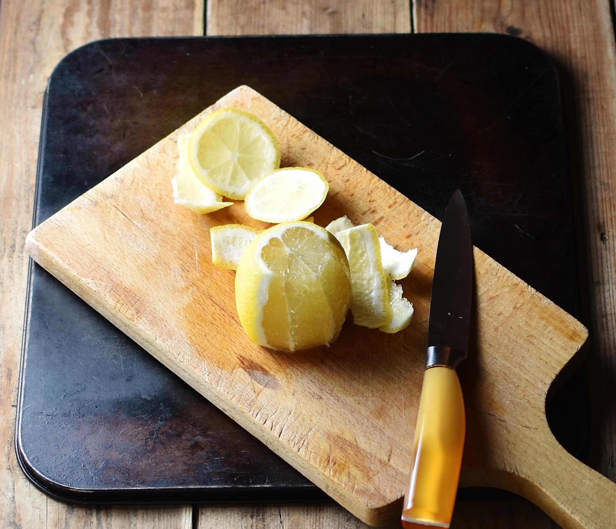 Lemon and peel with knife on top of cutting board.