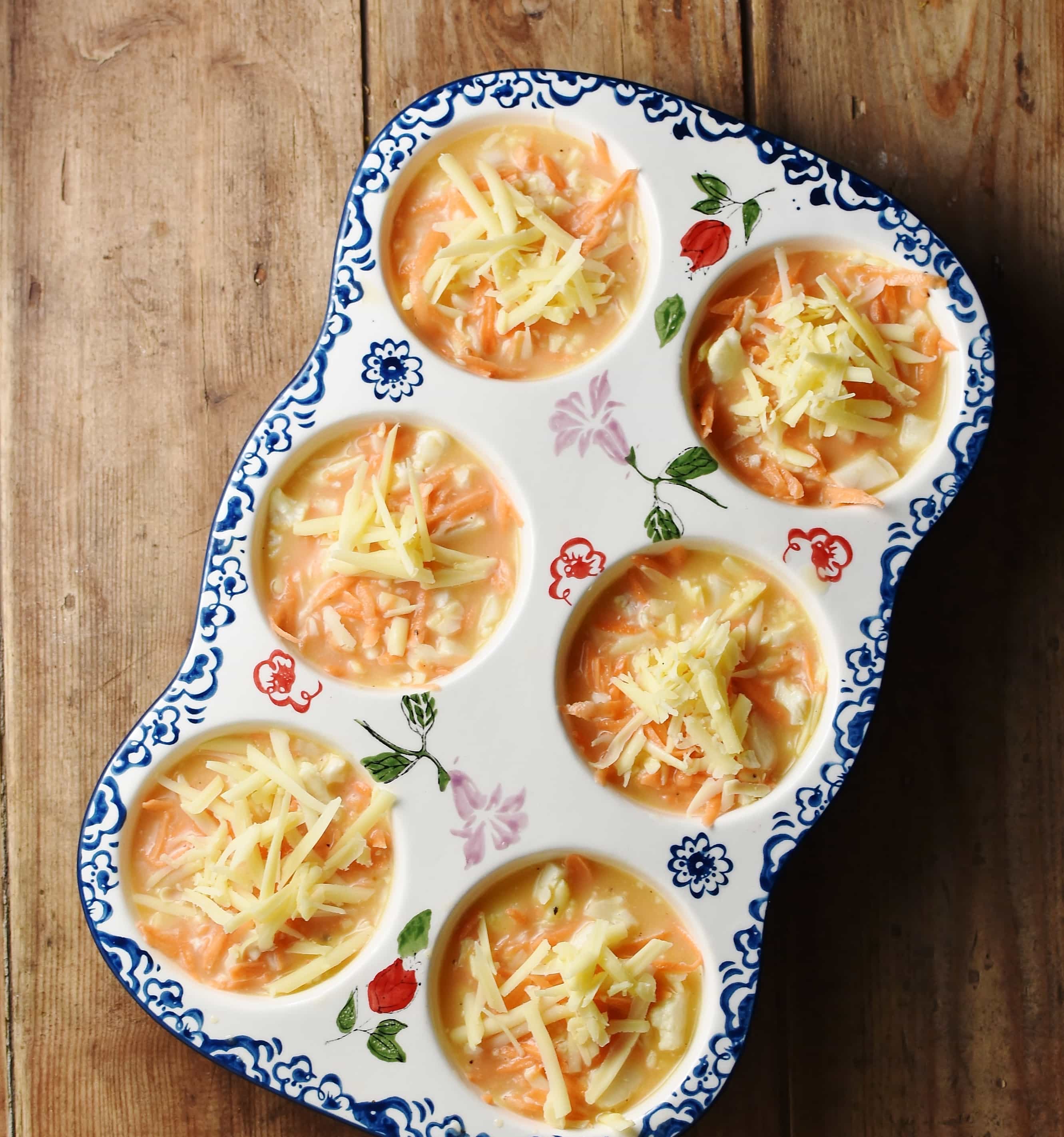 Sweet potato and egg mixture in 6-hole ceramic muffin pan with blue flower pattern.