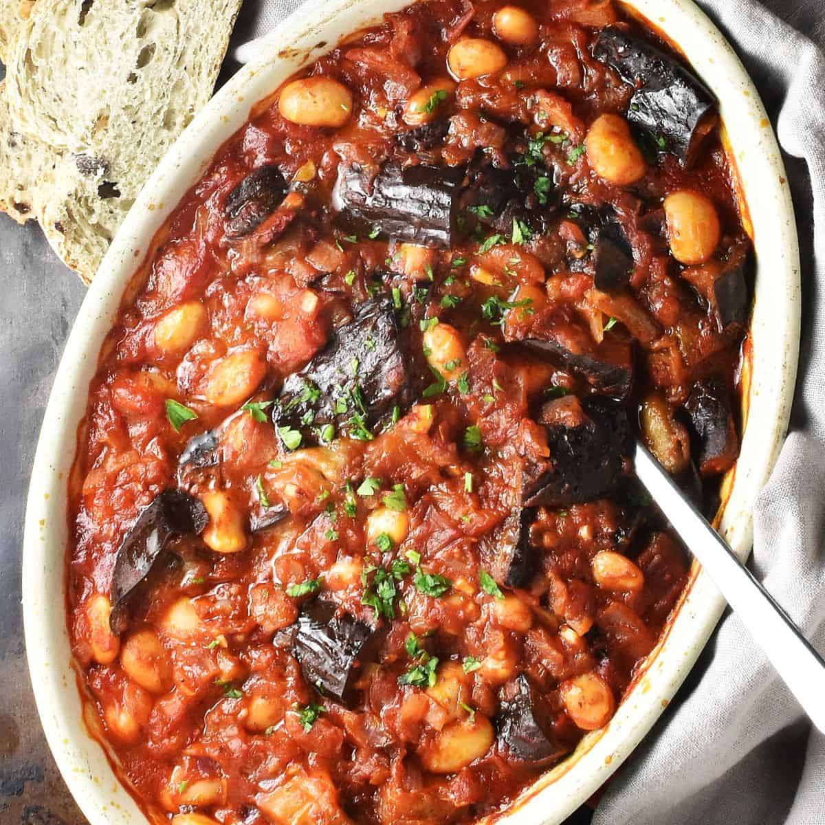Top down view of baked eggplant casserole in oval dish with spoon.