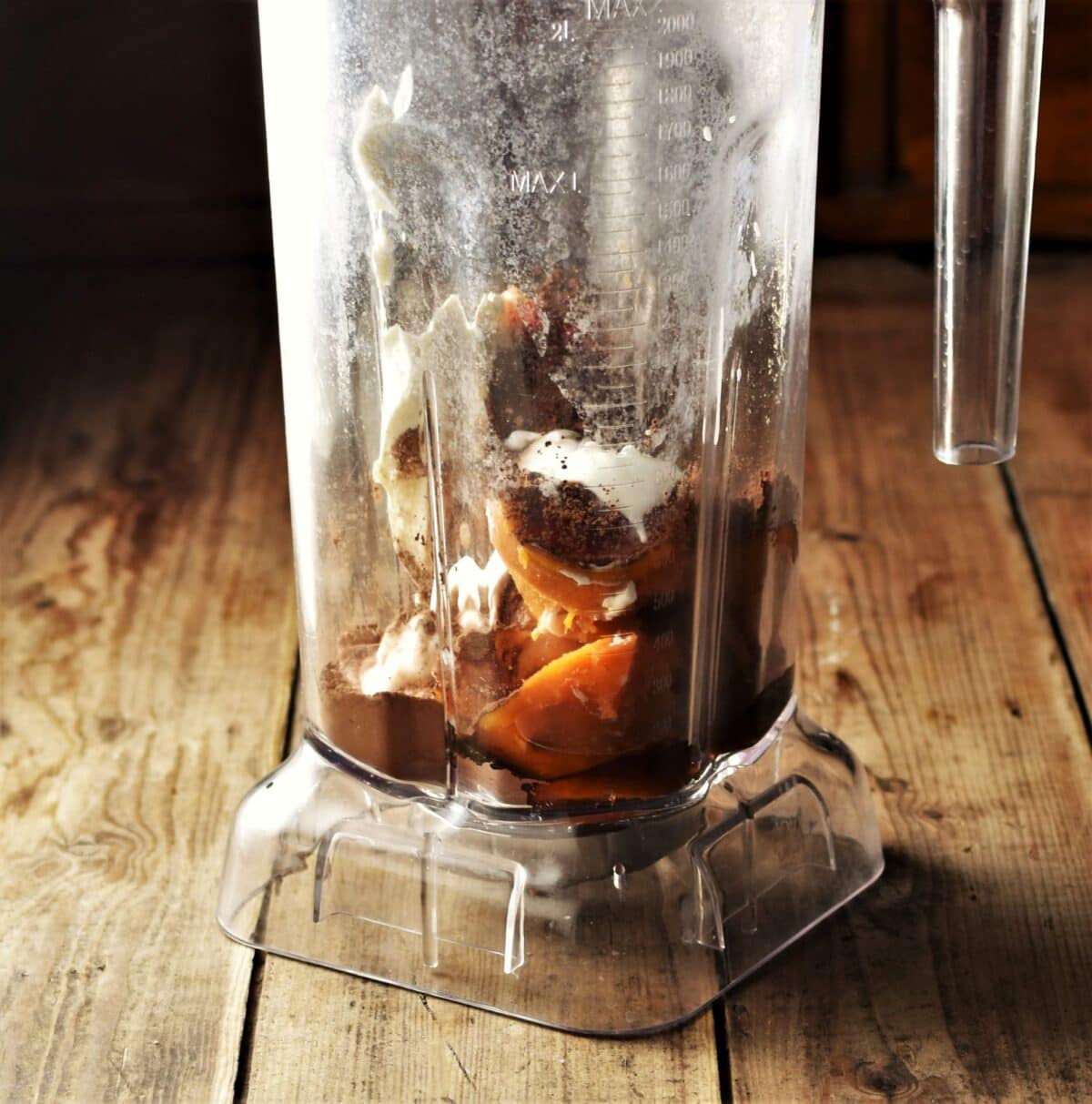Side view of blender containing chopped sweet potato, cocoa and yogurt.