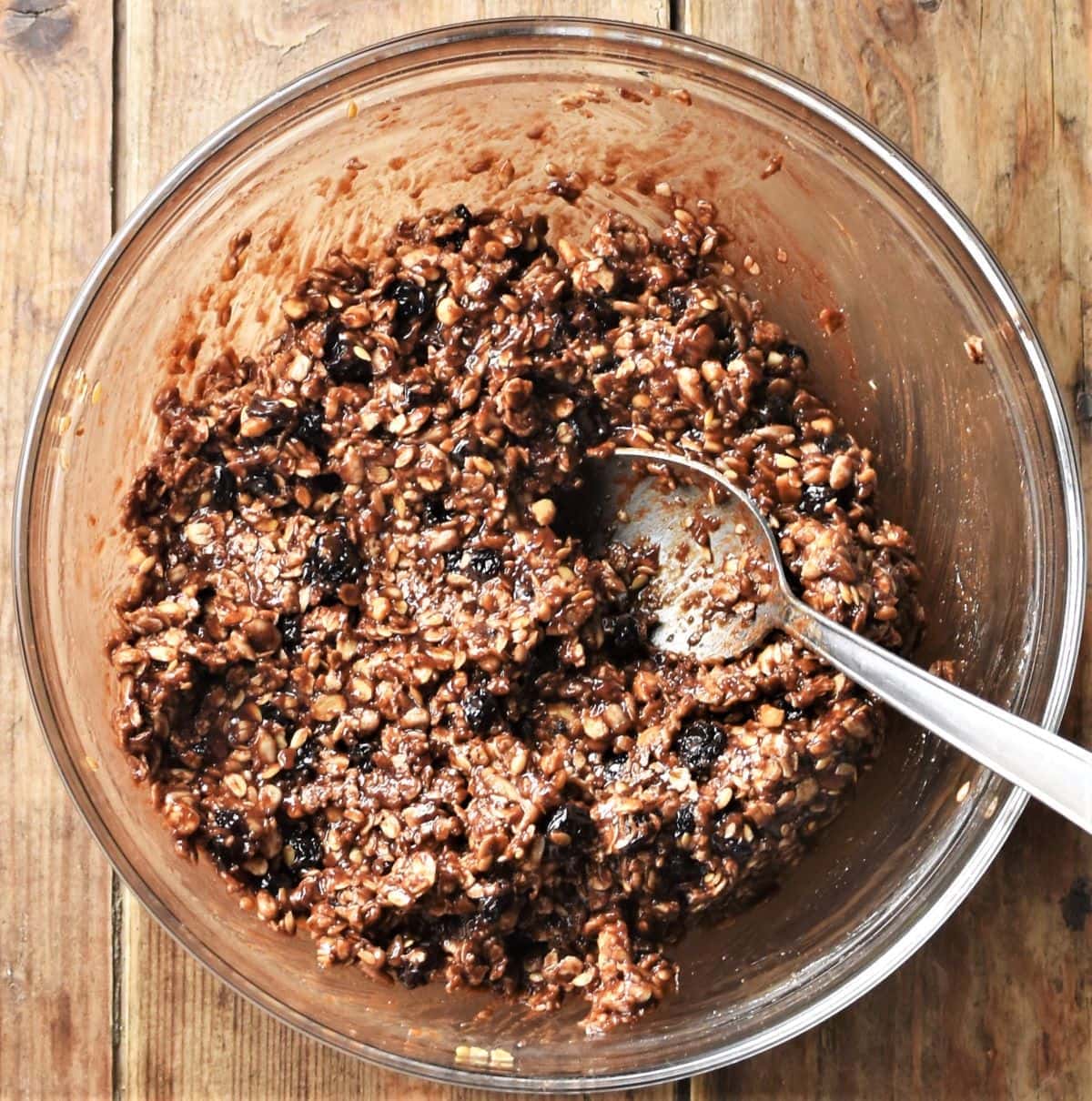 Oat, nut and chocolate mixture in bowl with spoon.