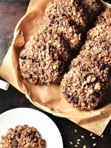 Top down view of chocolate oatmeal cookies on top of parchment and small plate.