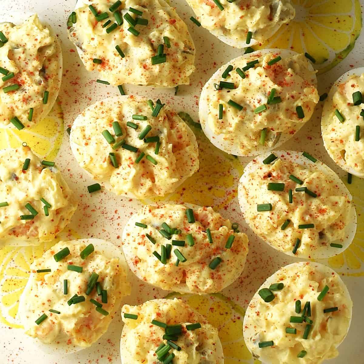 Top down view of potato salad deviled eggs with chives on yellow plate.