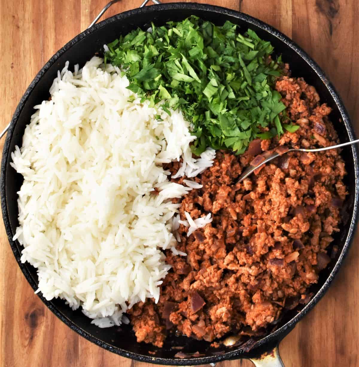 Ground turkey, cooked rice and fresh herbs in large shallow pan.