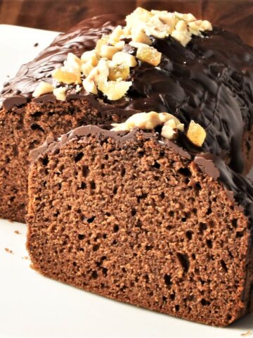 Side view of gingerbread loaf cake topped with chocolate and nuts.