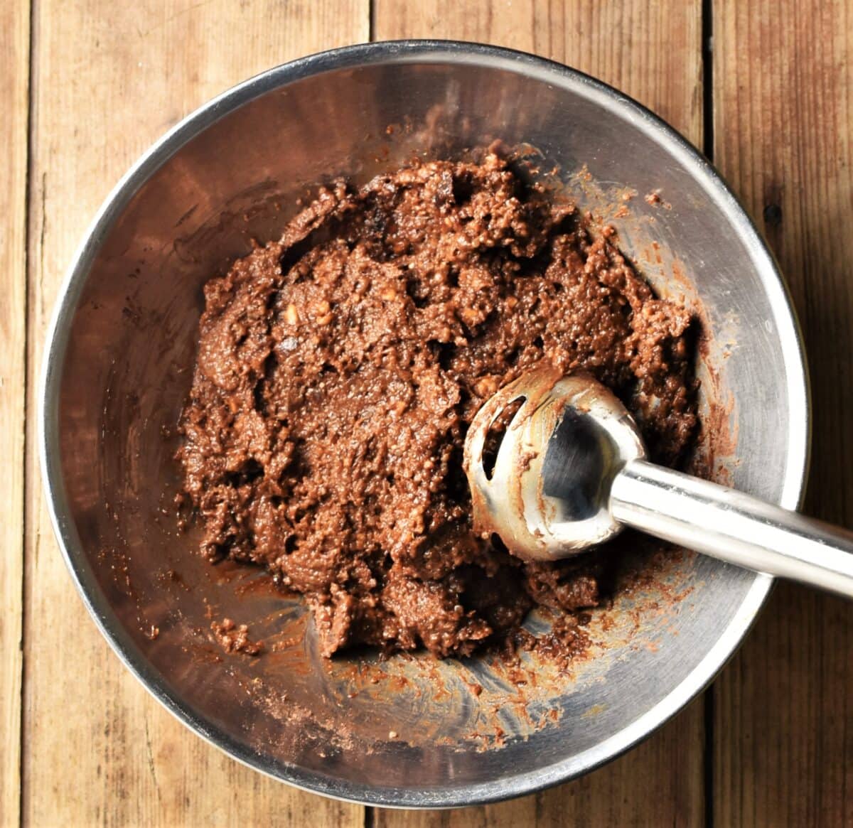 Quinoa chocolate mixture in large metal bowl with stick blender end piece.