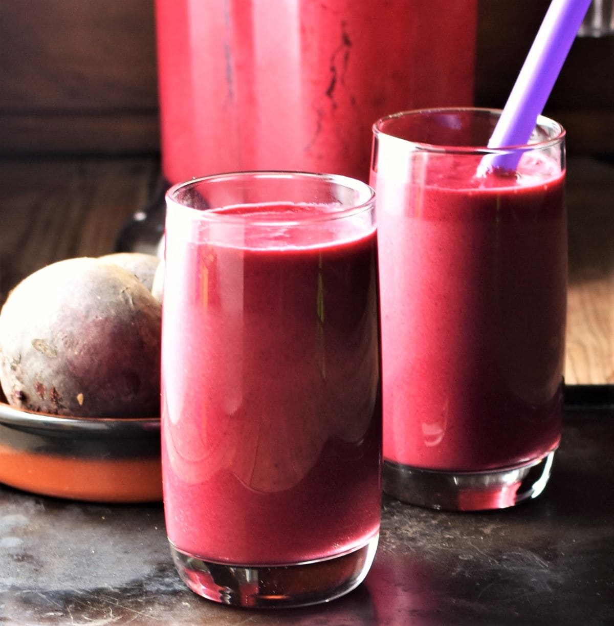 Smoothie in 2 tall glasses and raw beet in background.