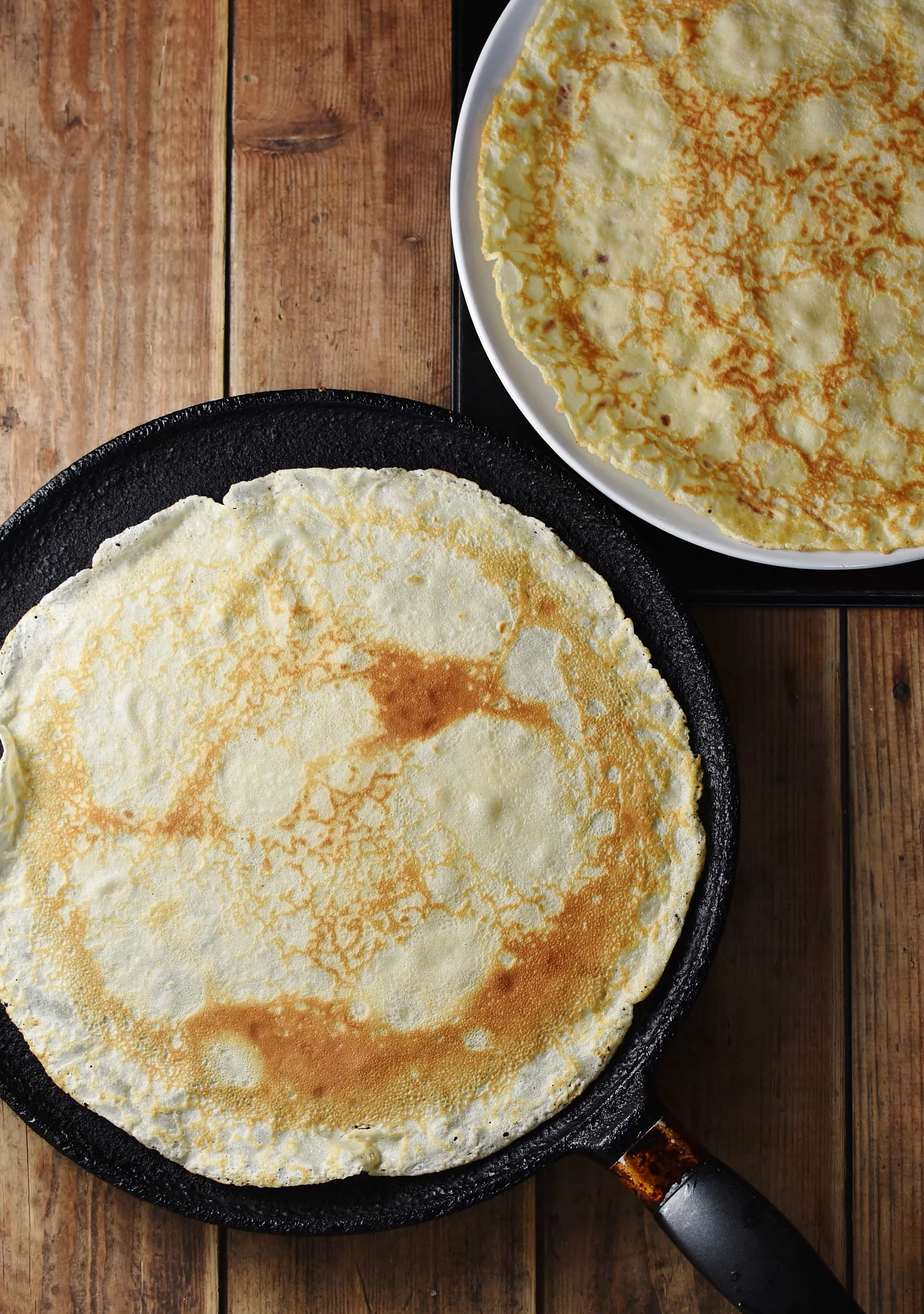 Large crepe in pancake pan and on top of large plate.