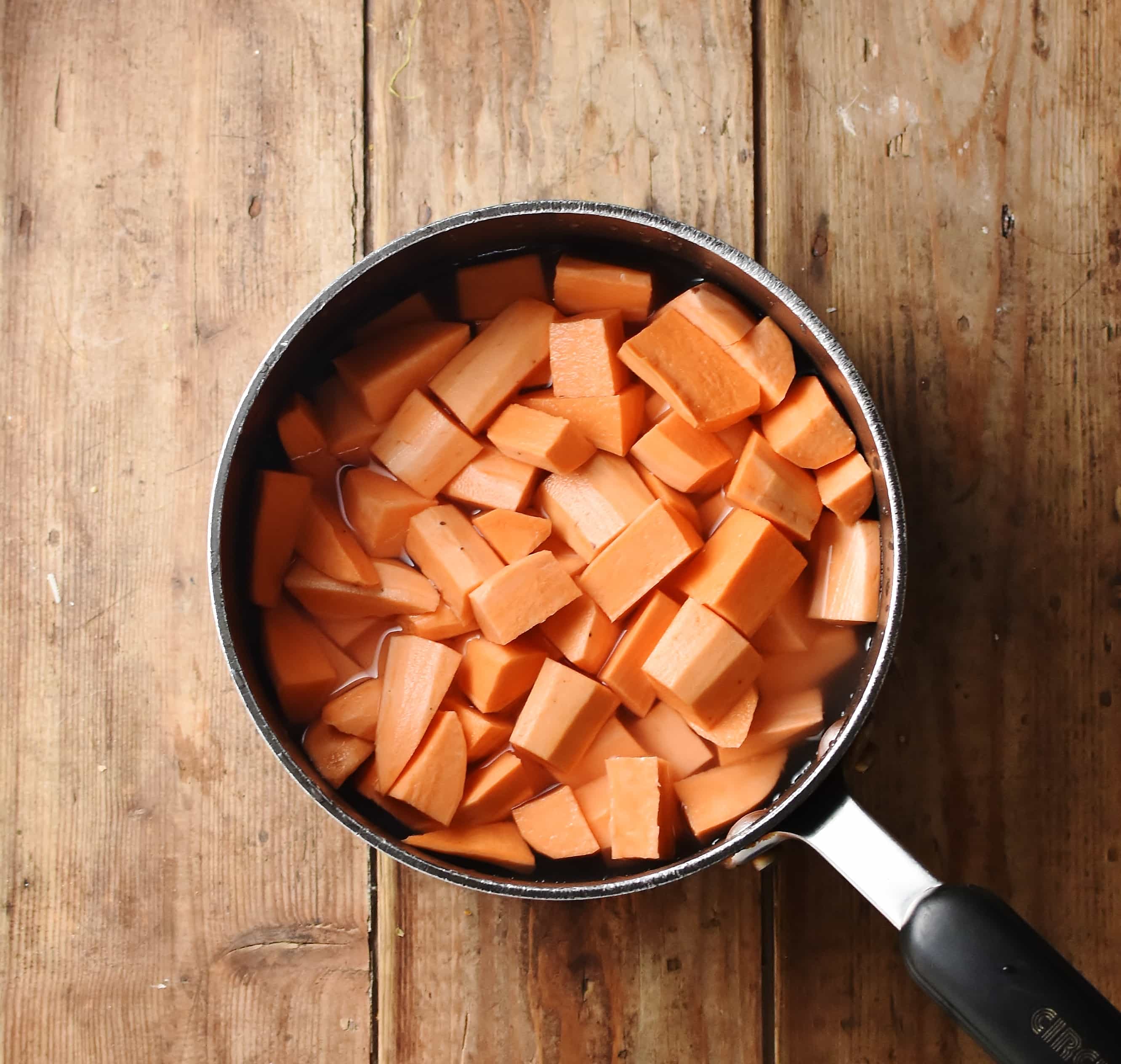 Cubed peeled sweet potato in saucepan with water. 