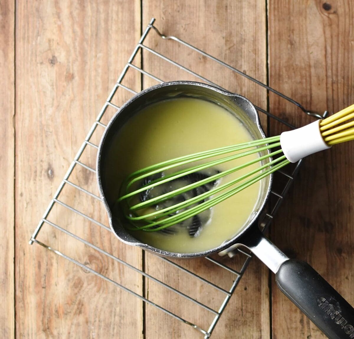 Roux sauce with green whisk in small saucepan.