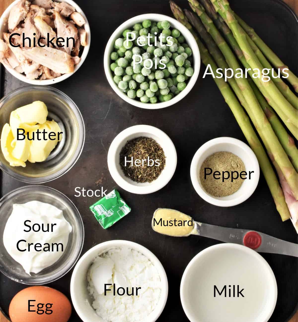 Ingredients for making chicken and asparagus pies in individual dishes.