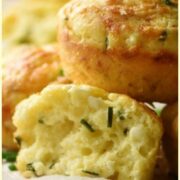 Close-up side view of cauliflower muffins with chives on top of baking paper.