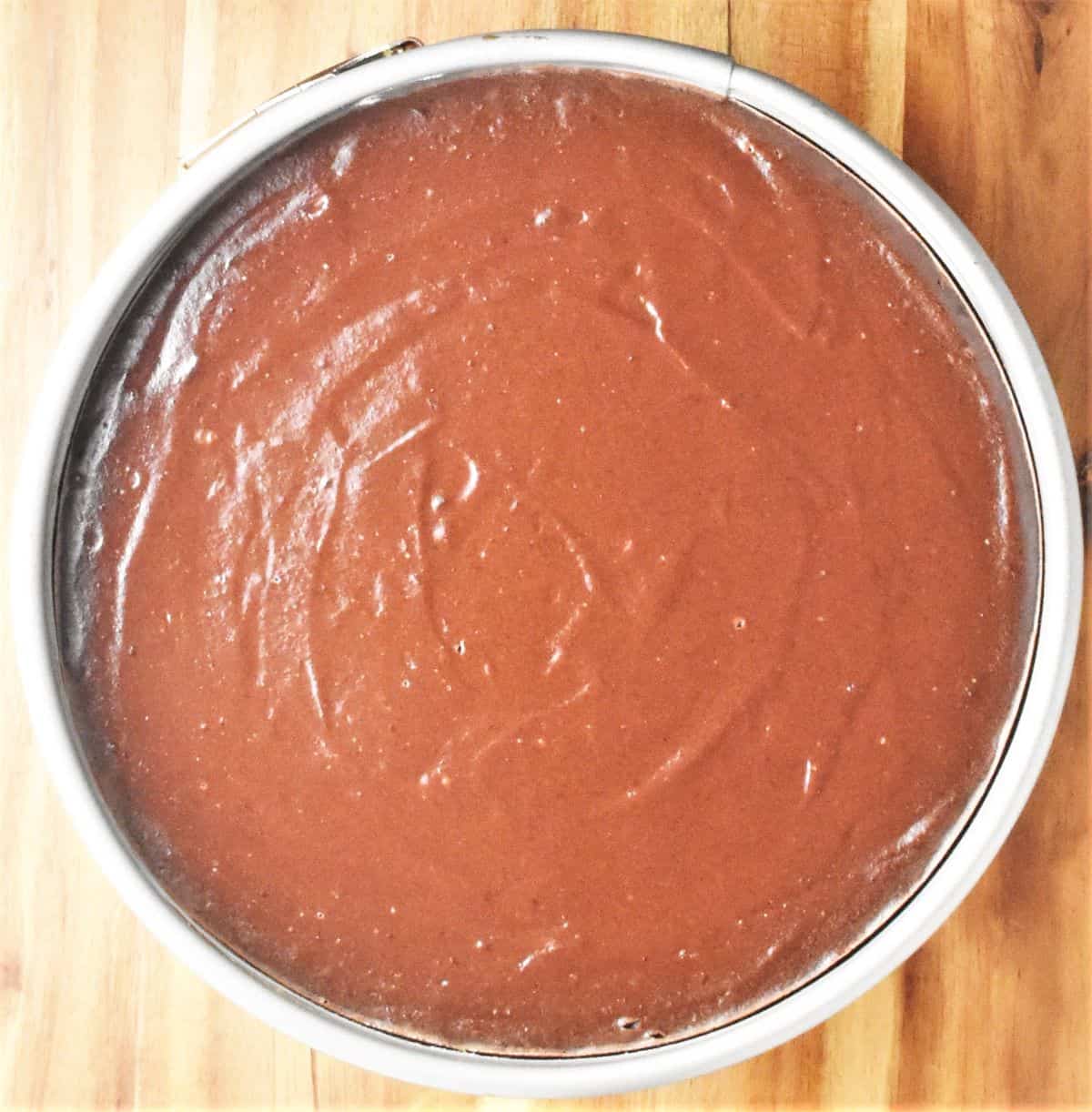 Top down view of baked chocolate cheesecake in pan.