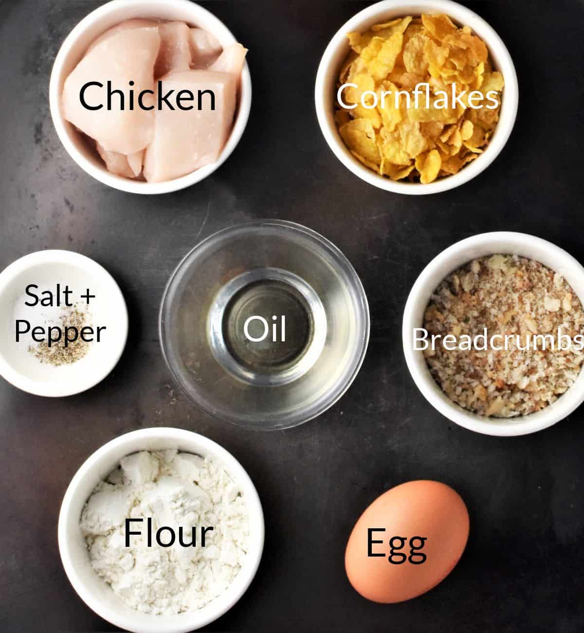 Ingredients for making cornflake chicken nuggets in individual dishes.