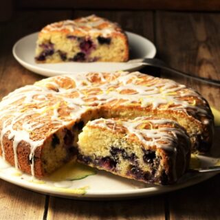 Side view of blueberry cake with slice on top of plate.