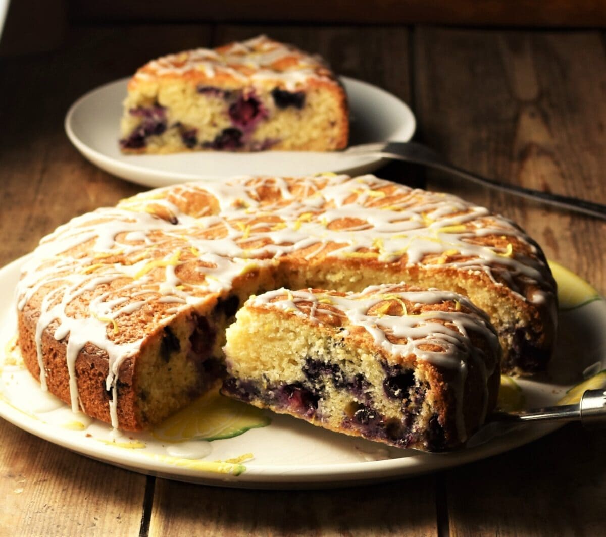 Side view of blueberry cake with slice on top of plate.