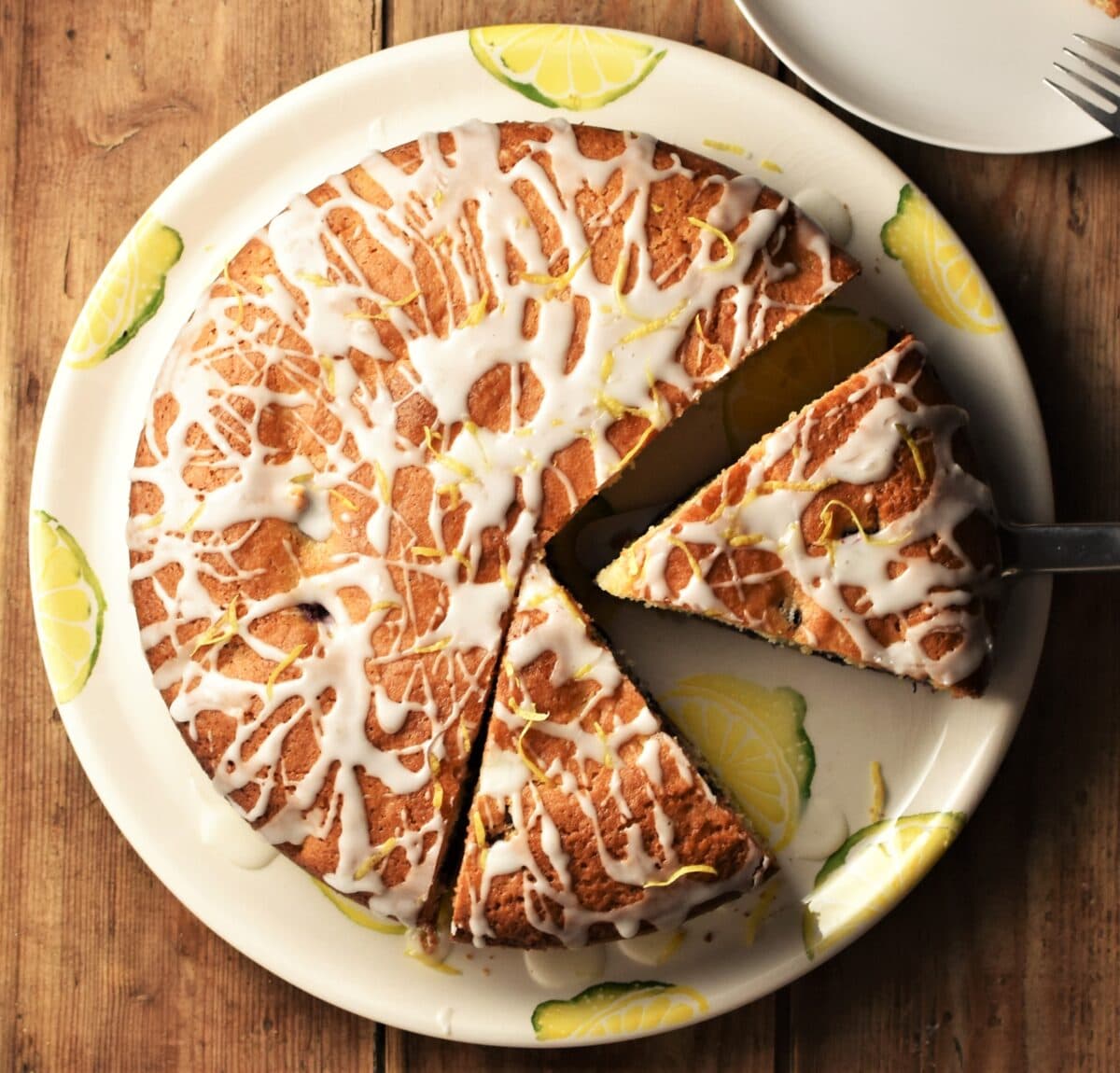 Top down view of blueberry cake with 2 slices on top of large plate.