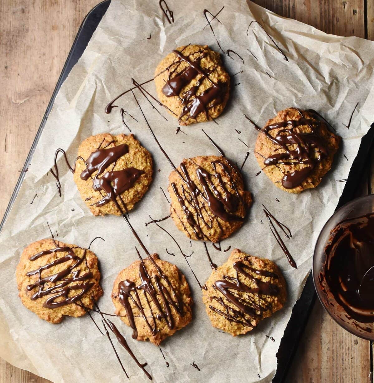 Pumpkin cookies with chocolate drizzle on top of paper.