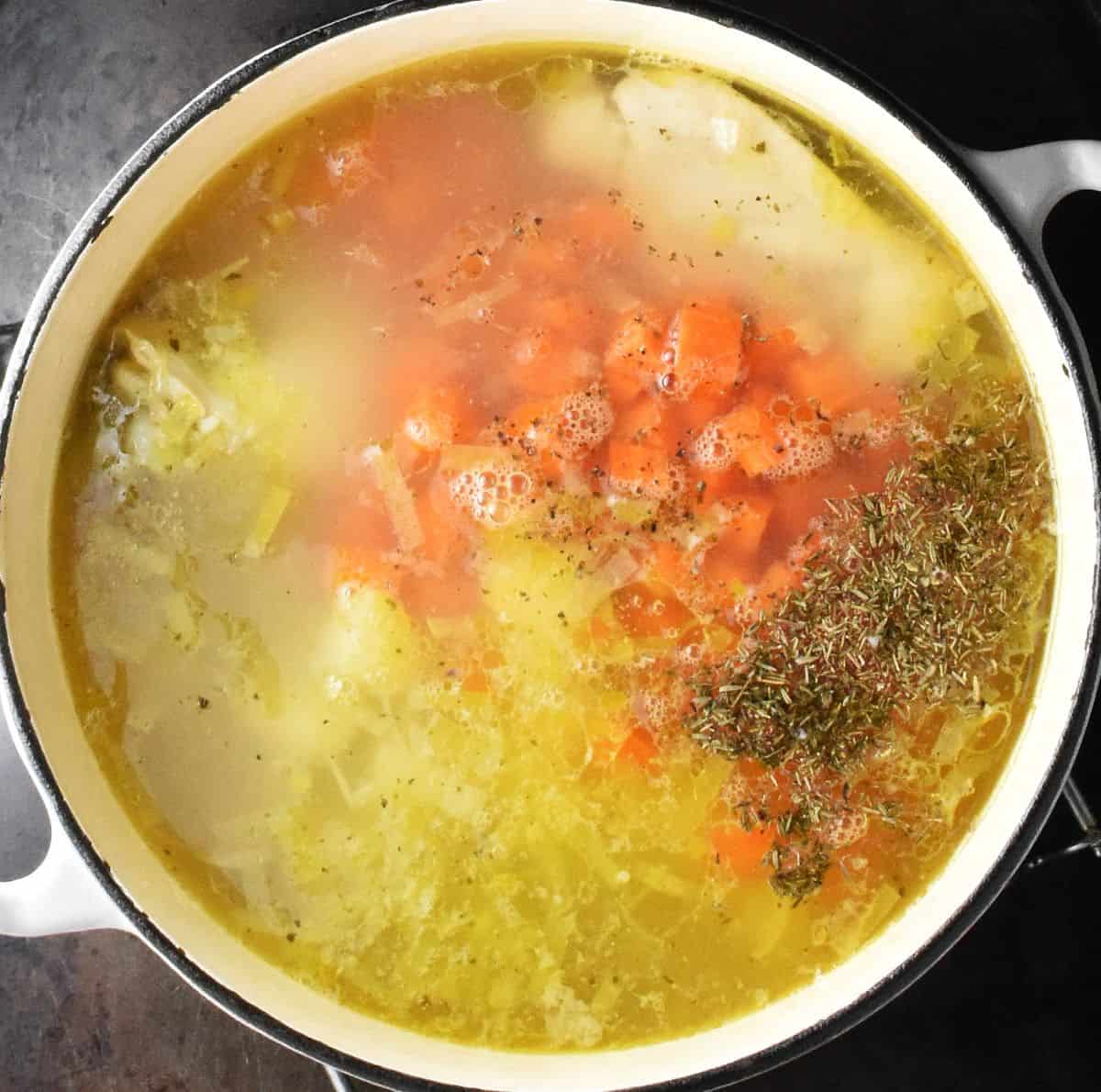 Chopped vegetables and chicken in white pot.