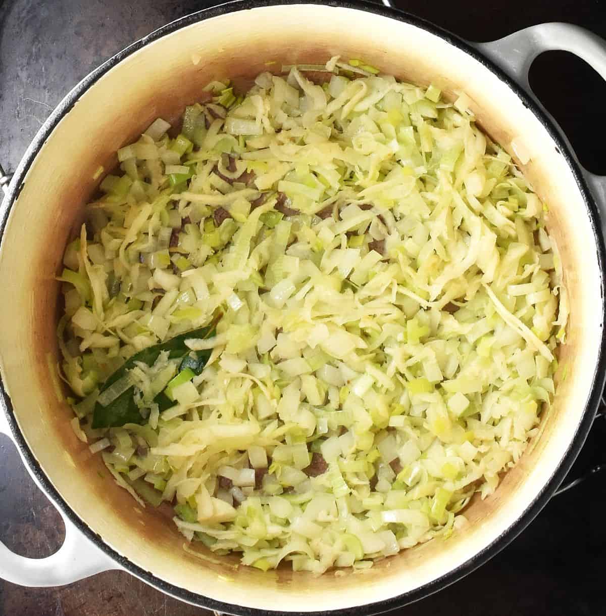Finely chopped vegetables with bay leaf in white pot.
