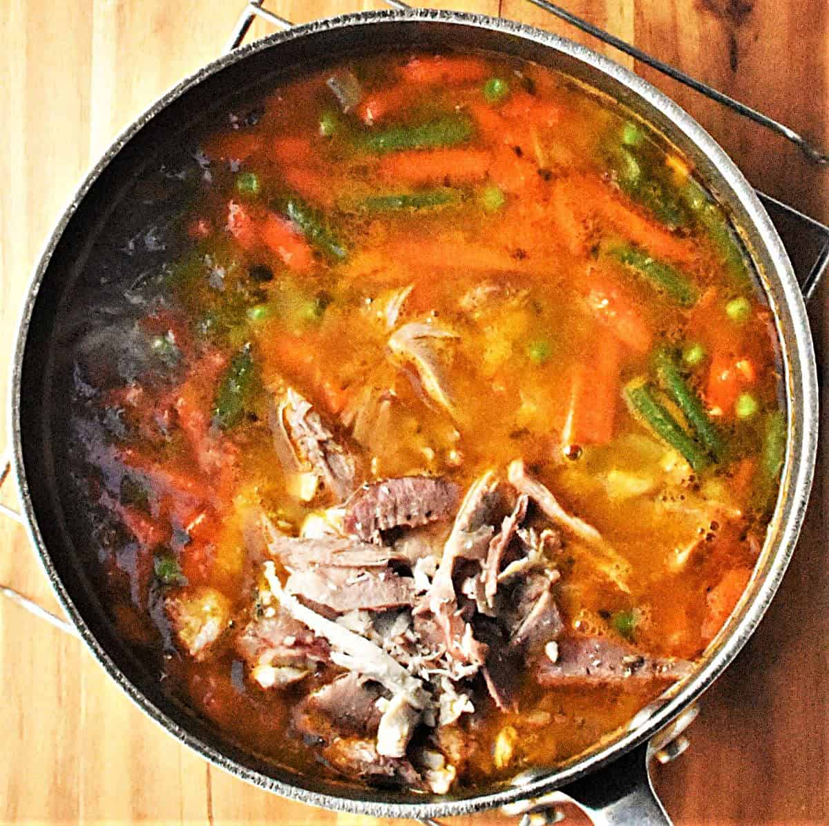 Chunky vegetable and turkey soup in large pot.