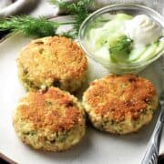 Close-up view of 3 breaded leftover turkey cakes with cucumber salad in background.