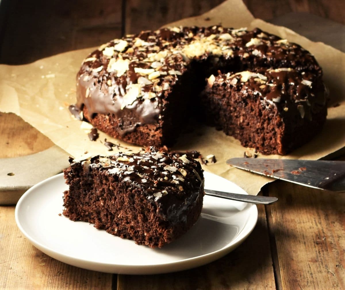 Side view of chocolate coconut cake slice with cake in background.