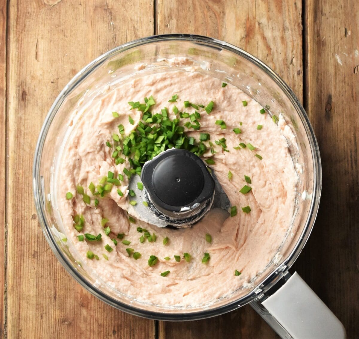 Creamy salmon spread mixture with chopped chives in blender bowl.