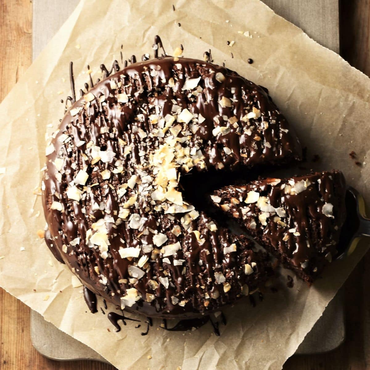 Top down view of cake with chocolate glaze and coconut flakes on top of parchment.