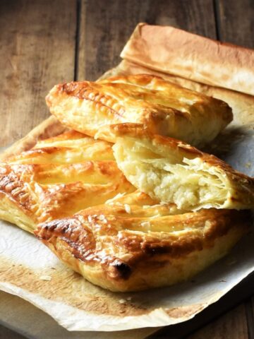 Side view of cheese and onion pasties with cauliflower on top of parchment paper.