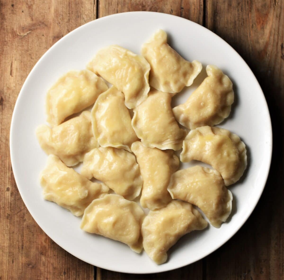 Cooked pierogi on top of white plate.