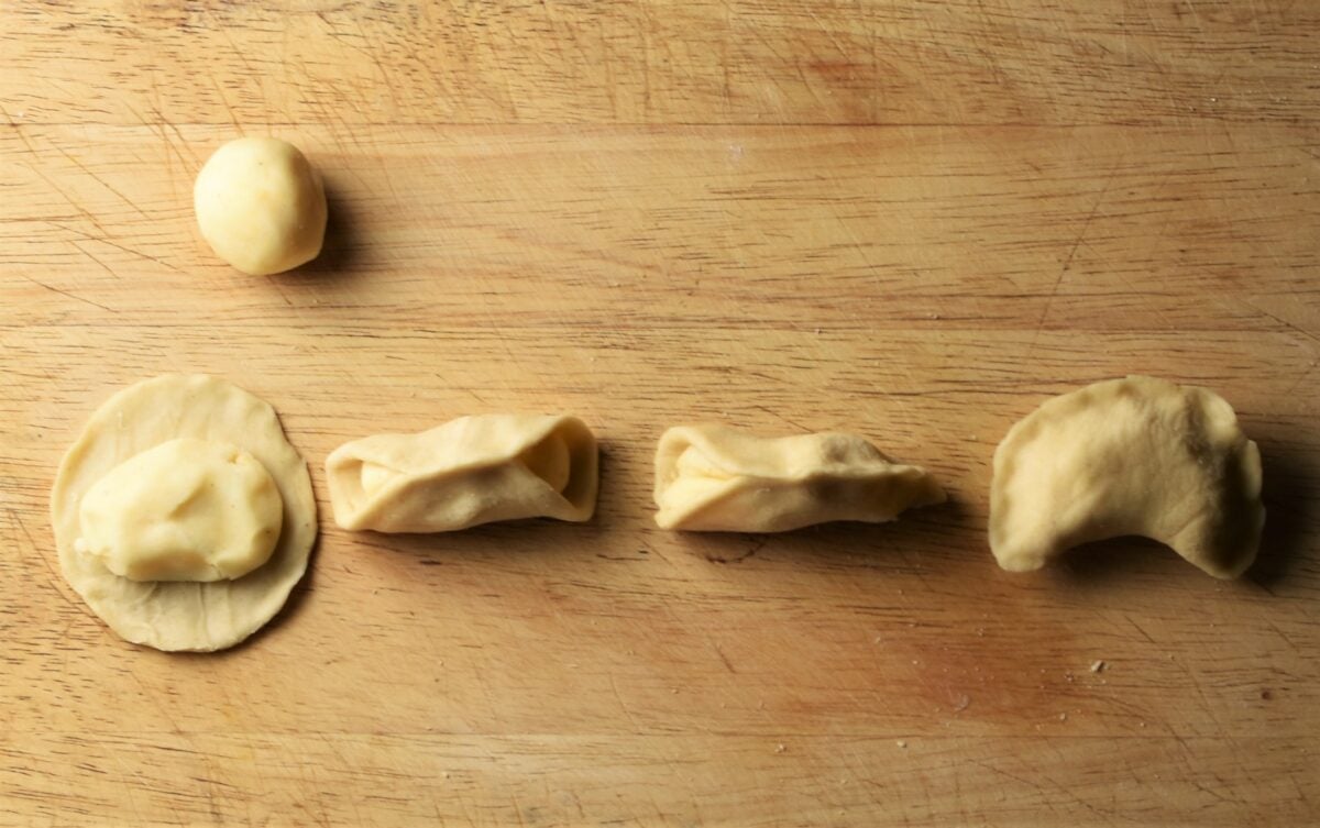 Forming perogies on top of wooden board.
