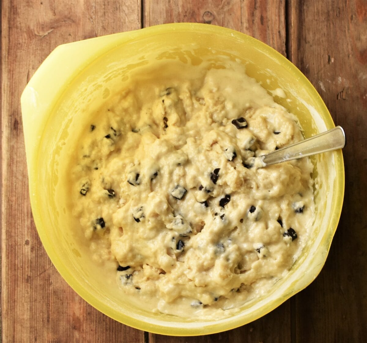 Marzipan cake batter in large yellow bowl with spoon.