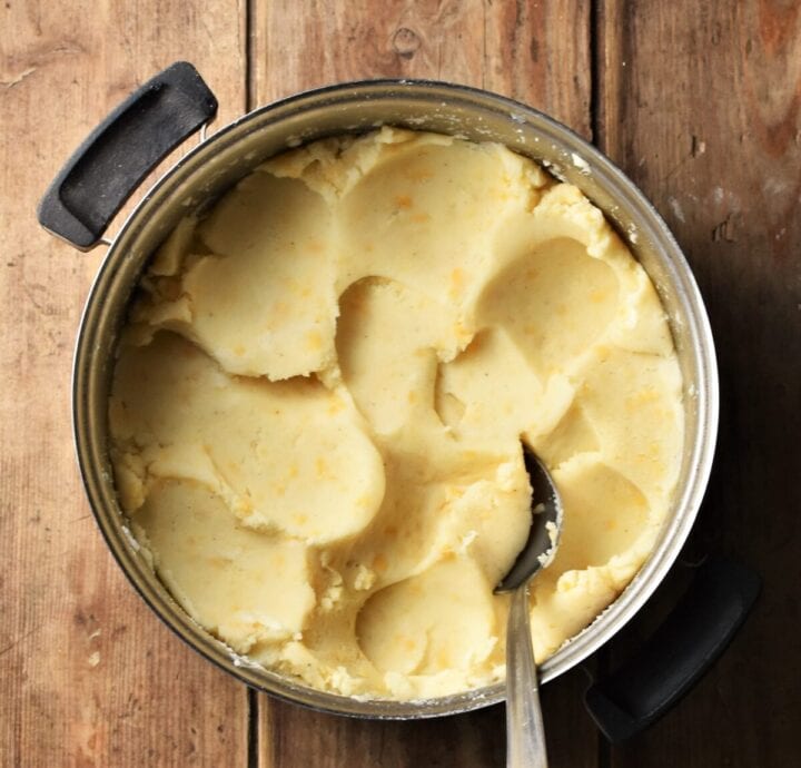 Mashed potato and cheese mixture in pot with spoon.