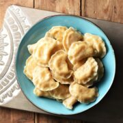 Top down view of homemade pierogies in blue bowl.