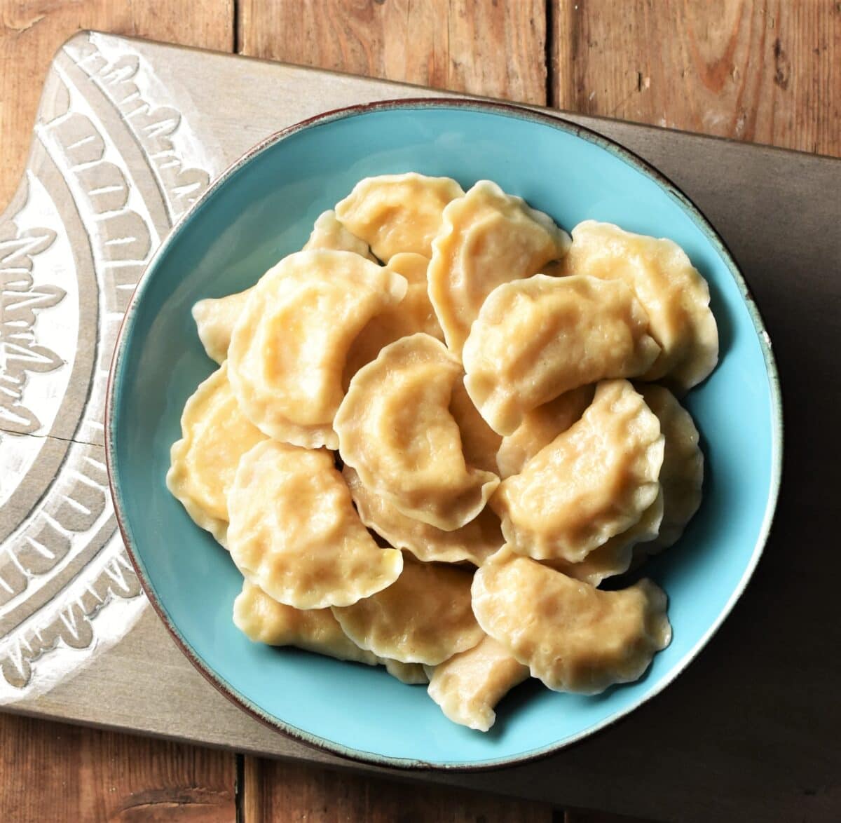 Top down view of homemade perogies in blue bowl.