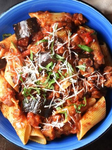 Top down view of eggplant pasta sauce with pasta in blue bowl.