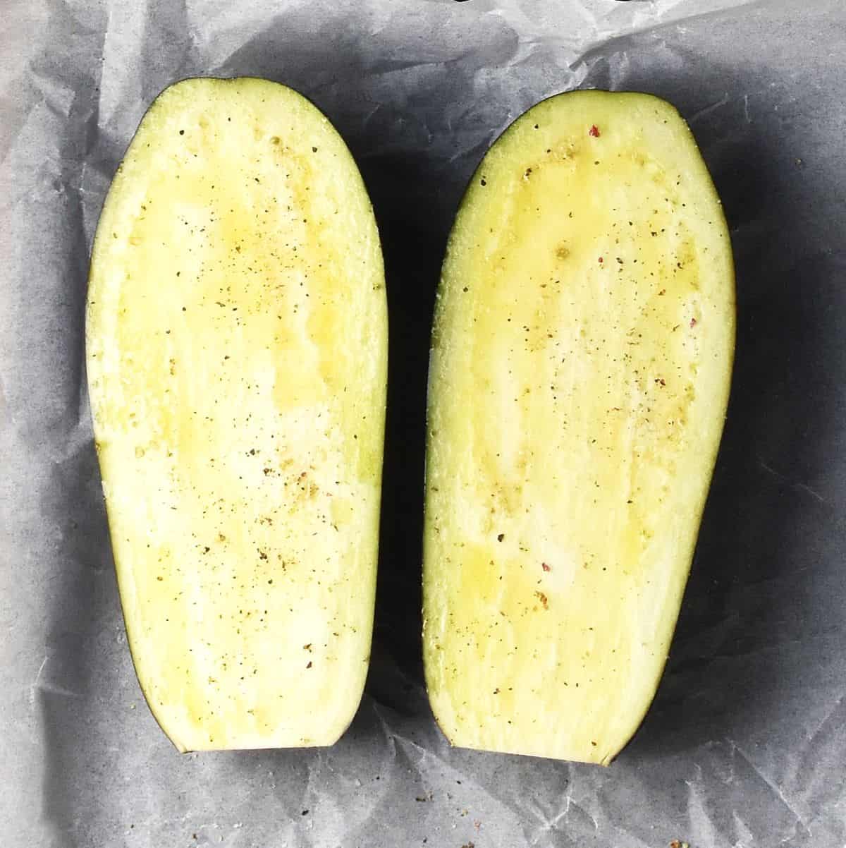 Two eggplant halves on parchment paper.