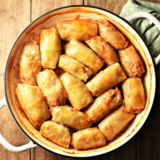 Top down view of cabbage rolls in large white shallow pan.