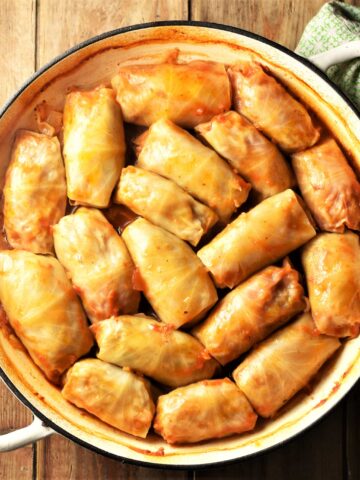 Top down view of cabbage rolls in large white shallow pan.