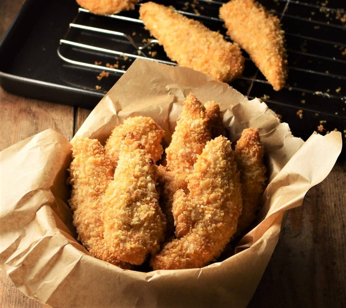 Side view of crispy chicken fingers in bowl lined with parchment.