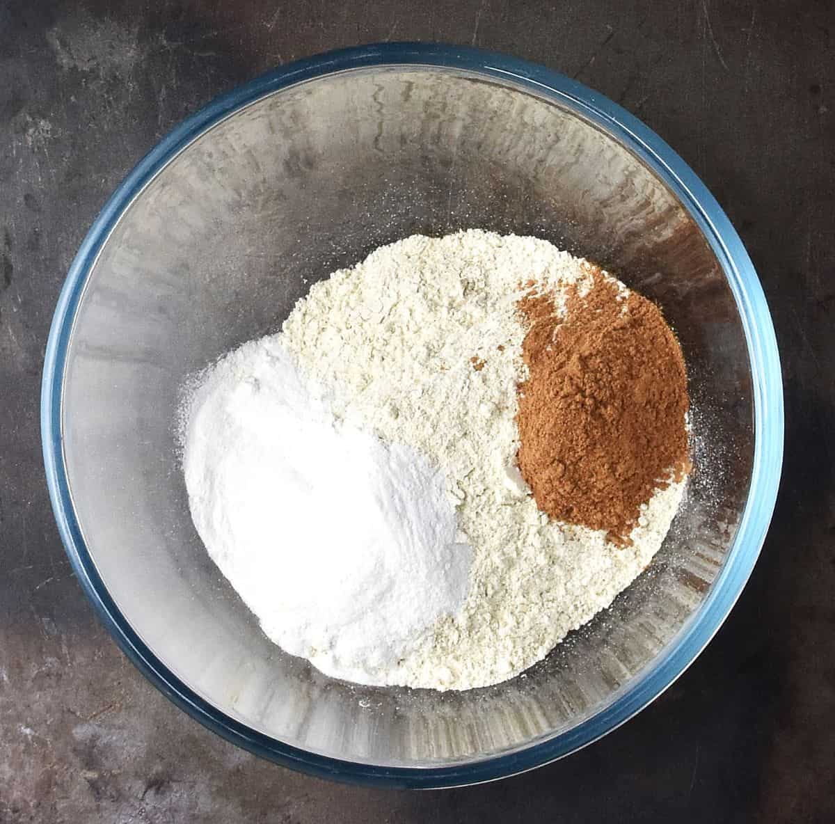 Top down view of quinoa flour with cinnamon in glass bowl.