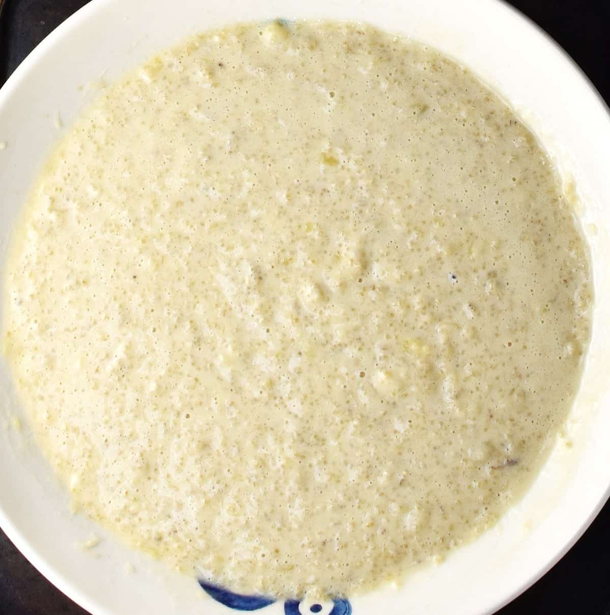 Wet quinoa pancake mixture in shallow white bowl.
