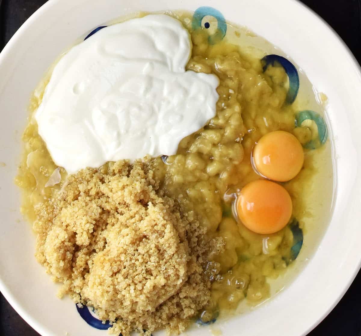 Cooked quinoa, mashed banana, yogurt and 2 raw eggs in large shallow bowl.