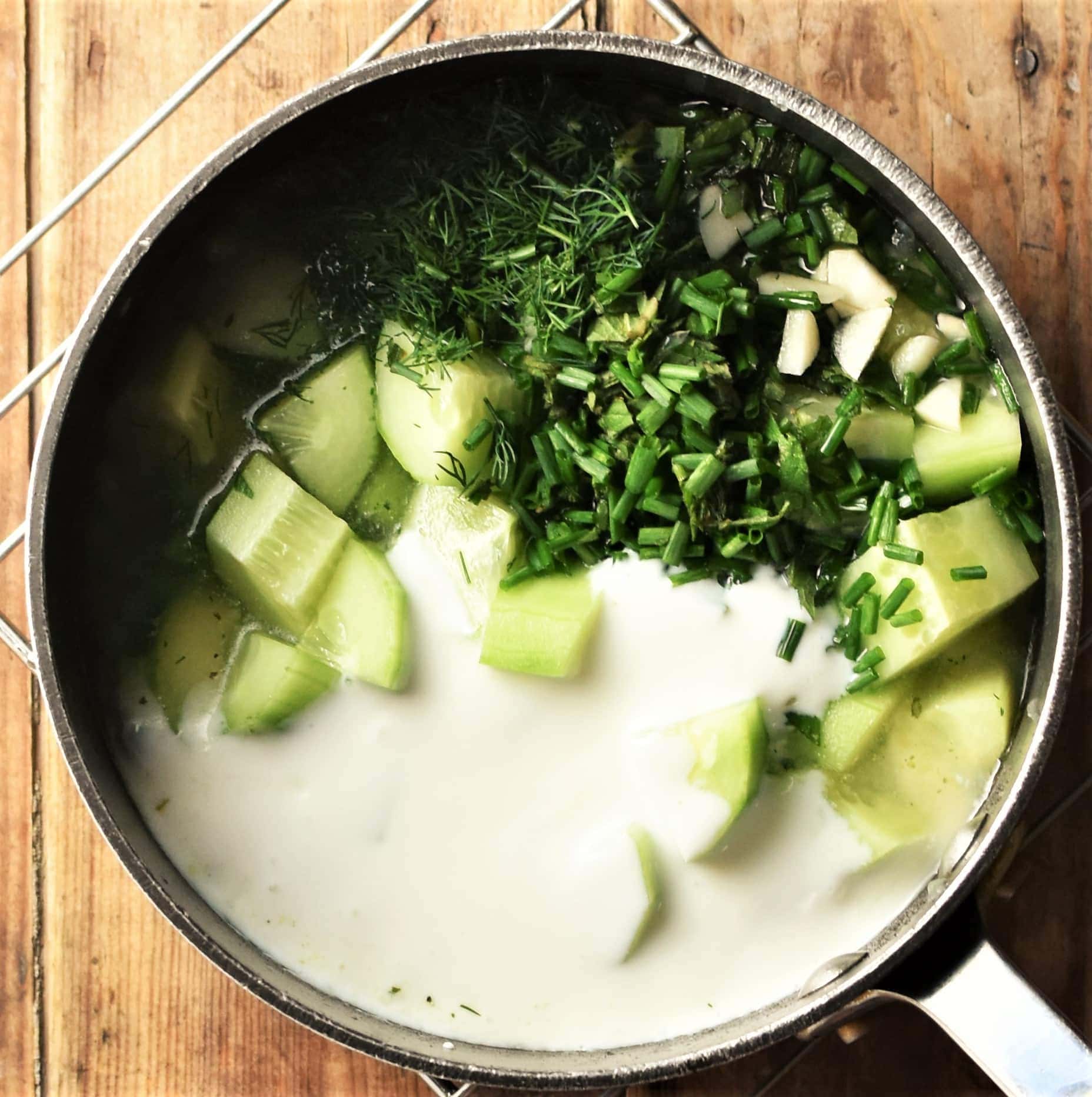 Cubed cucumber, herbs, peas and yogurt in pot.