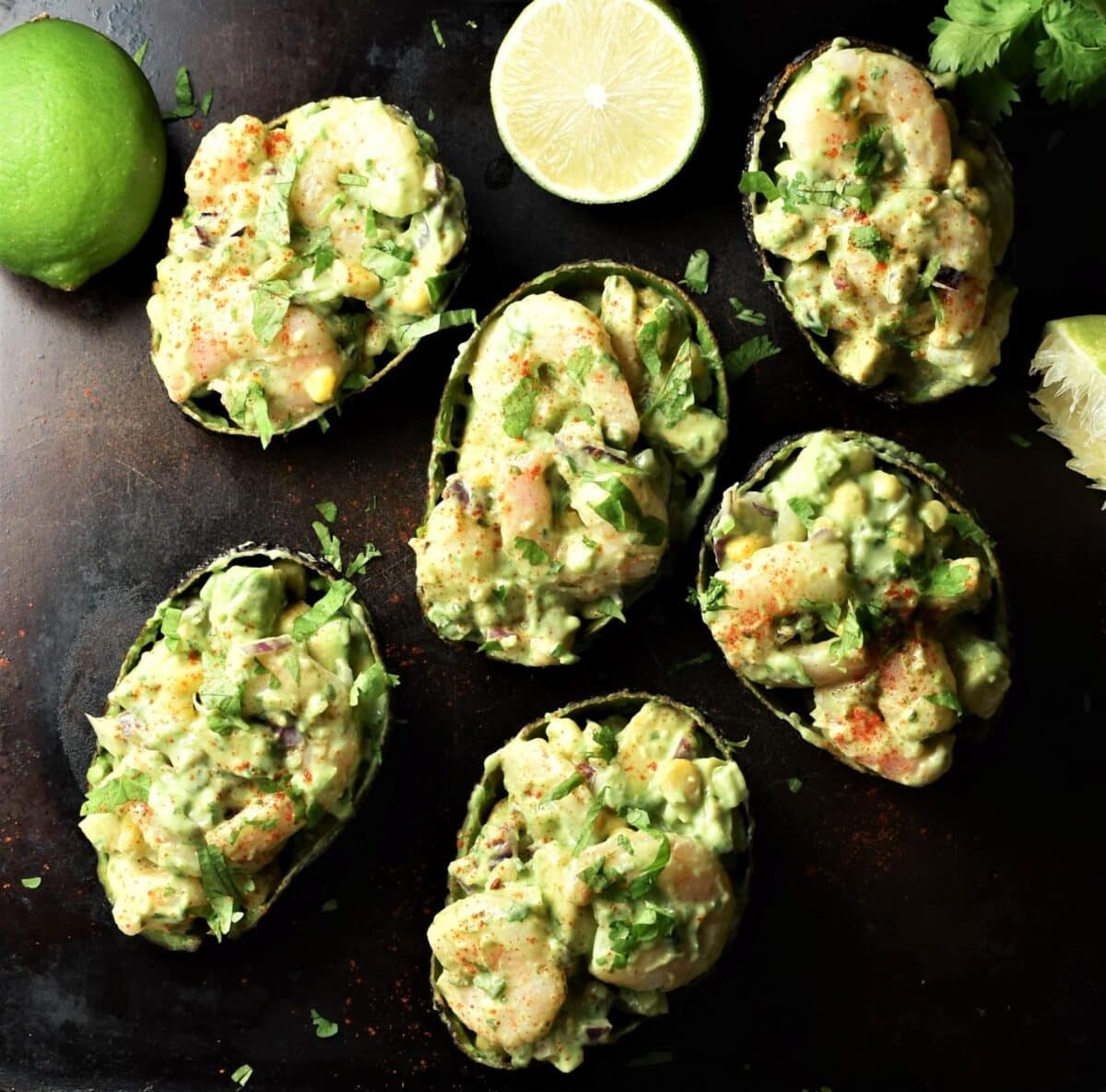Top down view of stuffed avocado halves with limes in background.