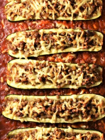 Baked vegetarian lentil stuffed zucchini in tomato sauce.